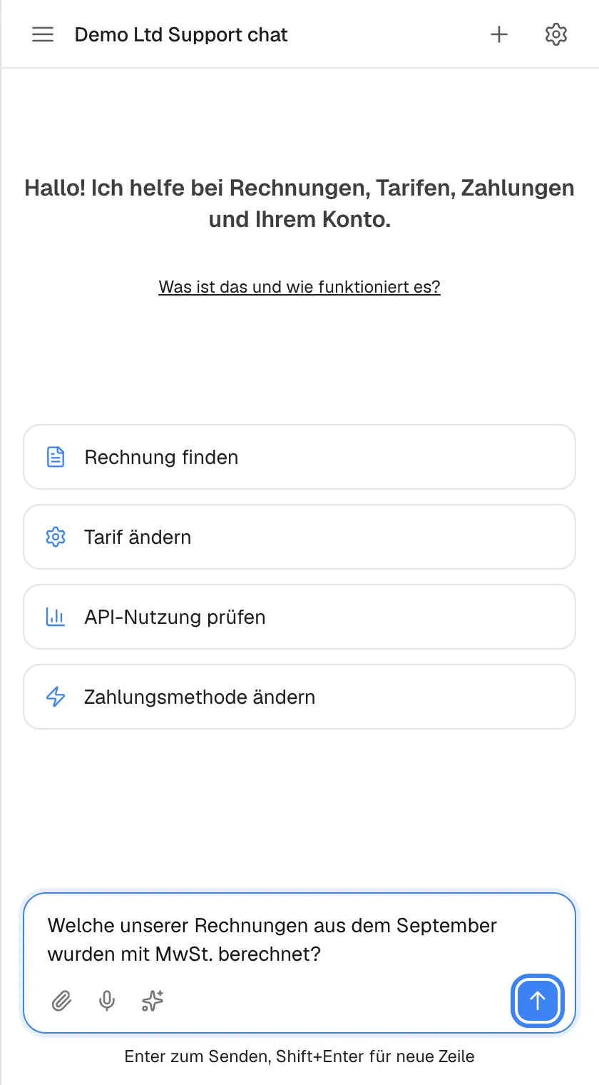Der Startbildschirm mit einer Frage im Eingabefeld: „Welche unserer Rechnungen aus dem September wurden mit MwSt. berechnet?“. Die blaue Senden-Schaltfläche mit Pfeil nach oben rechts im Feld, beschriftet „Nachricht senden“, ist hervorgehoben und aktiv. Links liegen die Büroklammer für Anhänge, das Mikrofon für die Spracheingabe und das Funkel-Symbol für Prompt-Shortcuts. Auch Enter sendet; Shift+Enter beginnt eine neue Zeile.